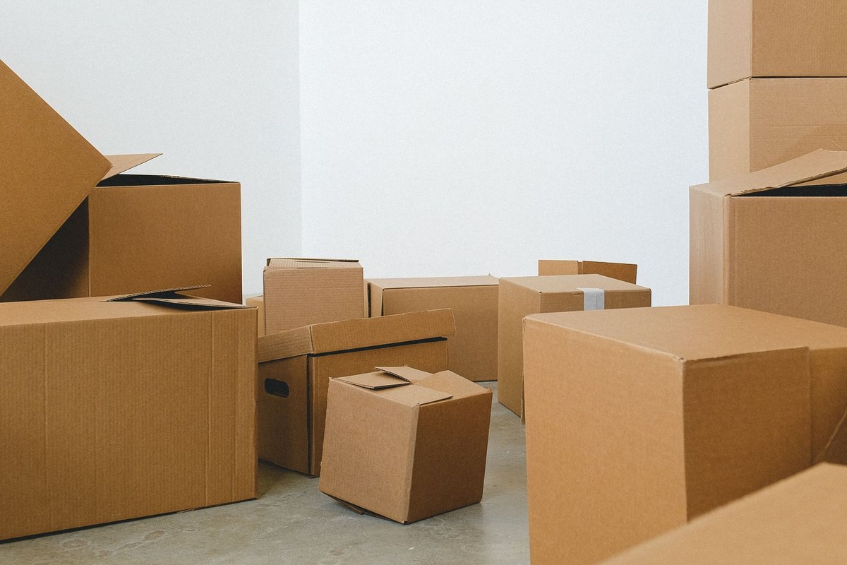 Brown cardboard boxes of many sizes heaped on a gray floor
