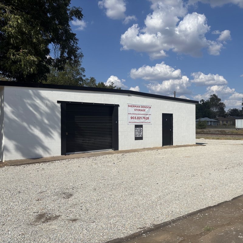 Black roll-up door and a banner on the white block wall of the storage building